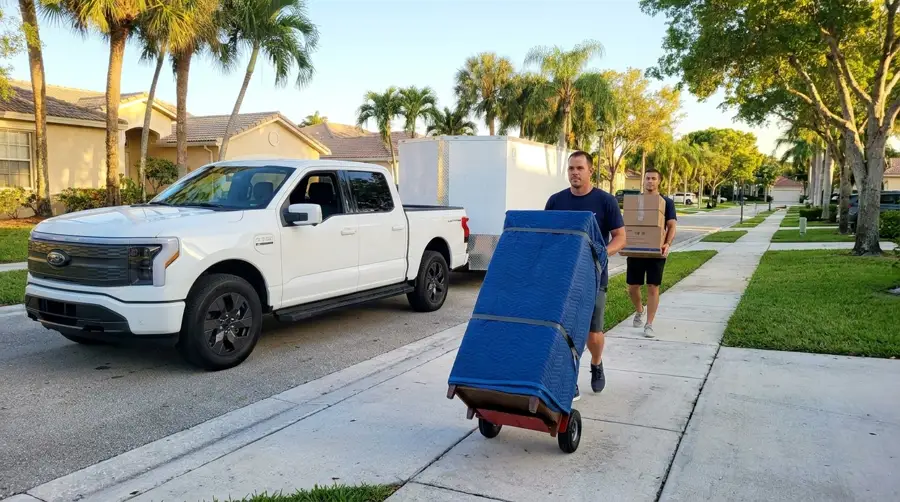 The Hauling Duo carrying a blanket-wrapped dresser to their enclosed trailer
